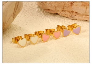 Detailed view of three pairs of golden heart stud earrings in white pink and purple enamel