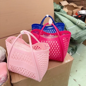 Three hollow silicone beach baskets in pink and blue colors stacked on a cardboard box