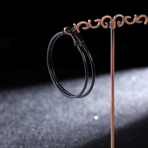Close-up of matte black hoop earrings on a vintage metal display stand for women