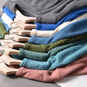 Detail view of stacked men's crewneck knit sweaters showing soft sherpa texture and colors