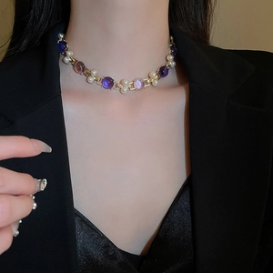 Gros plan d'un collier vintage doré avec gemmes bleues et perles sur un blazer noir