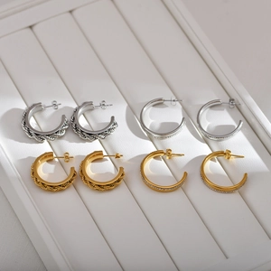Detail of twisted rope and rhinestone pavé C-shaped earrings in gold and silver finish