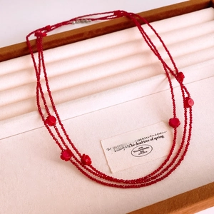 Detail of red multilayer beaded necklace with floral pendants on a jewelry tray