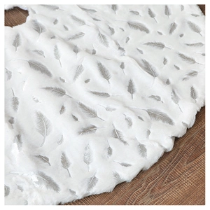 Detailed texture of white plush Christmas tree skirt with silver feather foil patterns