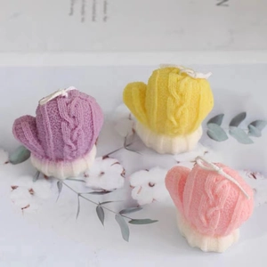 Three knitted glove shaped candles in purple yellow and pink for Christmas winter decor