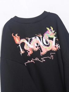 Detalle de sudadera negra con estampado de dragón colorido y letras de estilo callejero