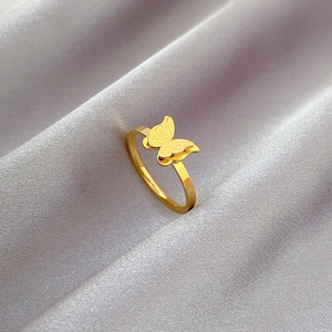 Detailed close-up of a double-layered butterfly ring in gold finish on silk fabric