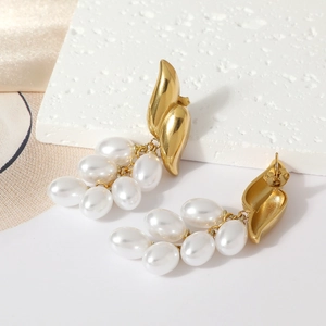 Elegant gold fringe earrings with white grape-shaped pearls on a marble background