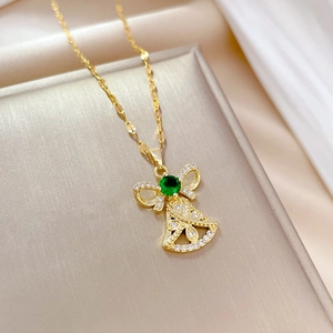 Macro shot of gold bell necklace featuring a green gemstone and paved crystals detail