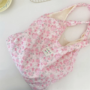 Detail of pink floral tote bag featuring embossed fabric texture and a chic brand label