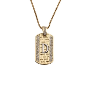 Détail d'un pendentif plaque dorée avec lettre D argentée et pierres de zircone cubique
