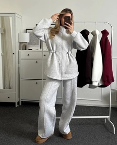 Detail of grey knitted tracksuit featuring a zipper hoodie and wide-leg drawstring pants