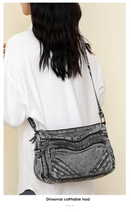 Detail of a vintage washed denim crossbody bag with multiple functional zip pockets
