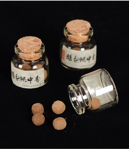 Detailed view of handmade brown incense pills in glass jars with cork stoppers on black background