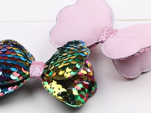 Detail of sequin bow hair clips for kids showing shiny texture and pink fabric pattern