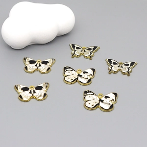 Macro shot of 6 butterfly skull pendants with gold borders and black white enamel finish