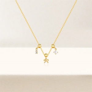 Detail of gold bow necklace with white pearl and sparkling zircon pendants for women