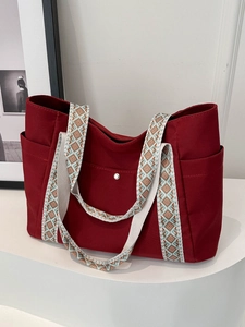 Dettaglio della borsa tote in tela rossa con tracolla geometrica e tasche laterali