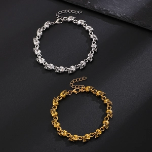 Dettaglio di bracciali teschio punk in metallo argento e oro con catene regolabili