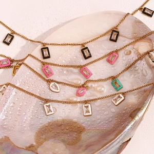 Detail of gold necklaces with colorful rectangular and teardrop pendants in a shell