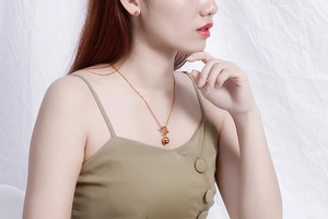 Detail view of golden spherical pendant necklace and matching ball stud earrings on model