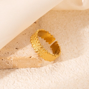 Détail d'une bague dorée réglable avec une texture perlée sur une surface en marbre