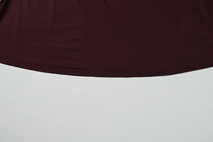 Dettaglio macro dell'orlo del vestito bordeaux con cucitura precisa a doppio ago