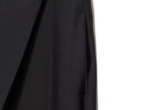 Close-up of high-quality stitching and pocket detail on black asymmetric casual pants