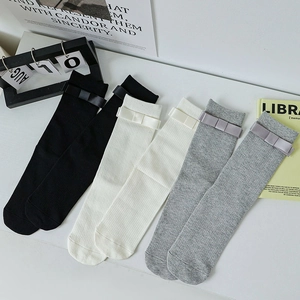 Detailed view of ribbed cotton crew socks with bow accents in black, cream, and grey
