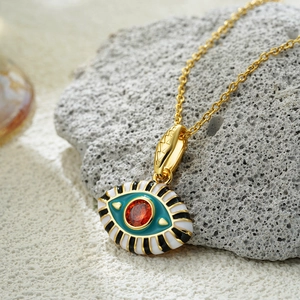 Macro shot of 18K gold plated evil eye pendant with enamel stripes on gray rock