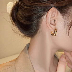 Close-up of model wearing gold tiger eye triangle hoop earrings in vintage aesthetic style