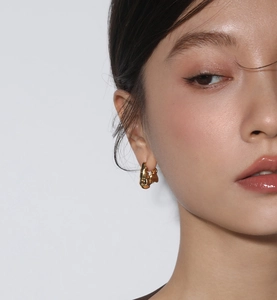 Detailed close-up of a gold irregular lava-style earring worn by a female model