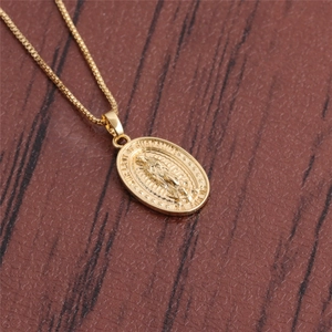 Detail of Our Lady of Guadalupe pendant on a gold necklace over a leather surface