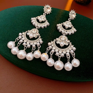 Macro detail of vintage silver tassel earrings with crystals and pearls on velvet