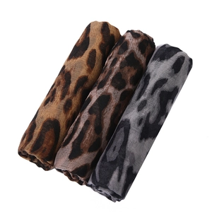 Detailed view of rolled leopard print scarves in brown, dark tan, and grey fabric tones