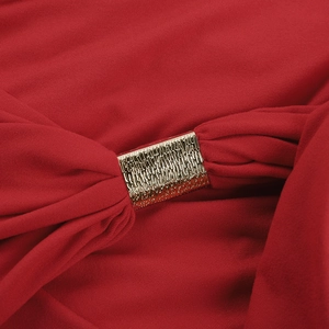 Detail of red halter dress featuring a textured gold metal buckle on the fabric