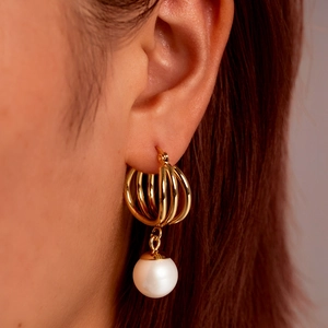 Boucles d'oreilles créoles dorées avec perle blanche portées par un mannequin