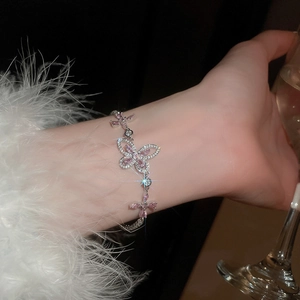 Detailed view of silver butterfly bracelet with pink zircon stones worn on the wrist