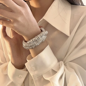 Close-up of textured silver wide lava cuff bracelet worn on a model with white shirt