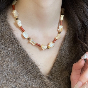 Detail of irregular shell mother-of-pearl beads and reddish-brown stones on the necklace