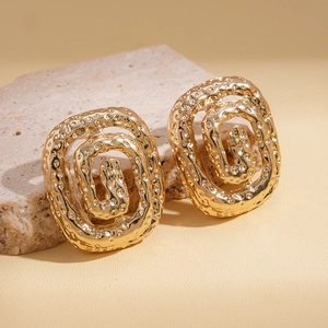 Detailed macro view of gold-colored hollow spiral earrings on textured stone base