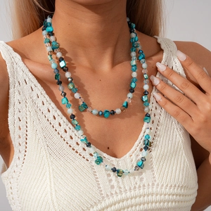 Détail d'un collier bohème multicouche avec turquoise et nacre sur gilet tricoté