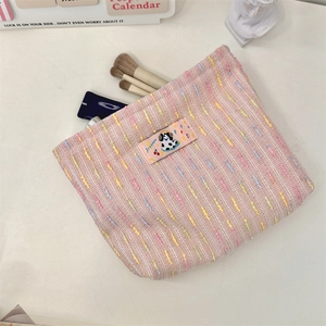 Vue détaillée d'une trousse à maquillage en tweed rose avec texture tissée colorée