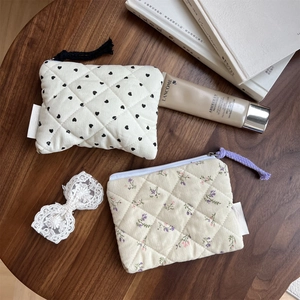 Quilted corduroy mini pouches with floral and heart patterns on a wooden desk