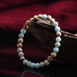 Beaded stone bracelet with light blue and reddish-brown gems on vintage wood base