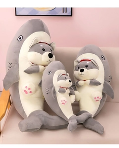 Three sizes of shark-shiba inu hybrid plush toys on a soft beige sofa in a cozy room