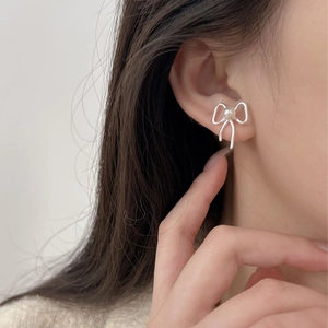 Close-up of bow knot pearl earrings in silver finish worn by a model for a chic look