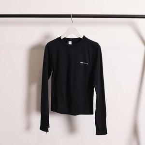 Detail of black slim fit yoga top featuring thumb holes and white chest logo print