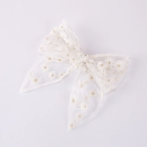 Detail of embroidered daisy pattern on white lace bow hair clip for girls