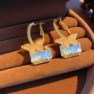 Details von luxuriösen Gold-Schmetterlingsohrringen mit schillerndem Kristall auf Samt